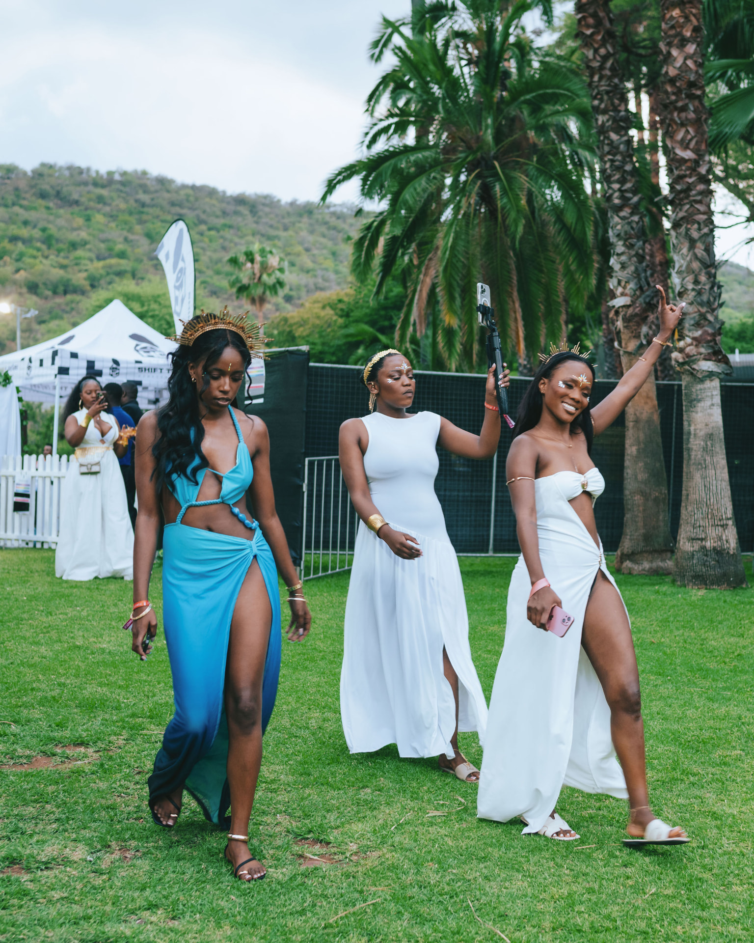 Three guests in elegant white and blue outfits walking on the resort lawn