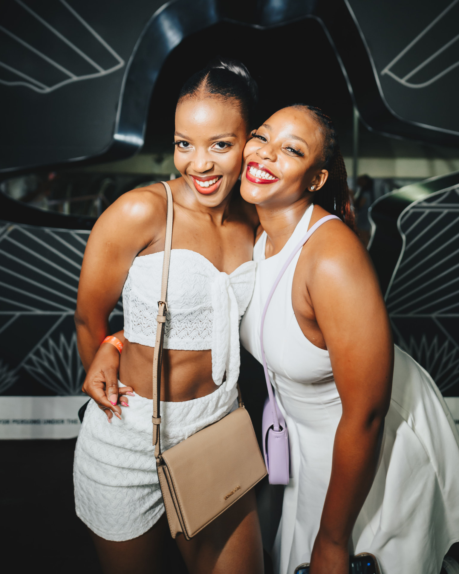 Two guests in white outfits smiling together at the event
