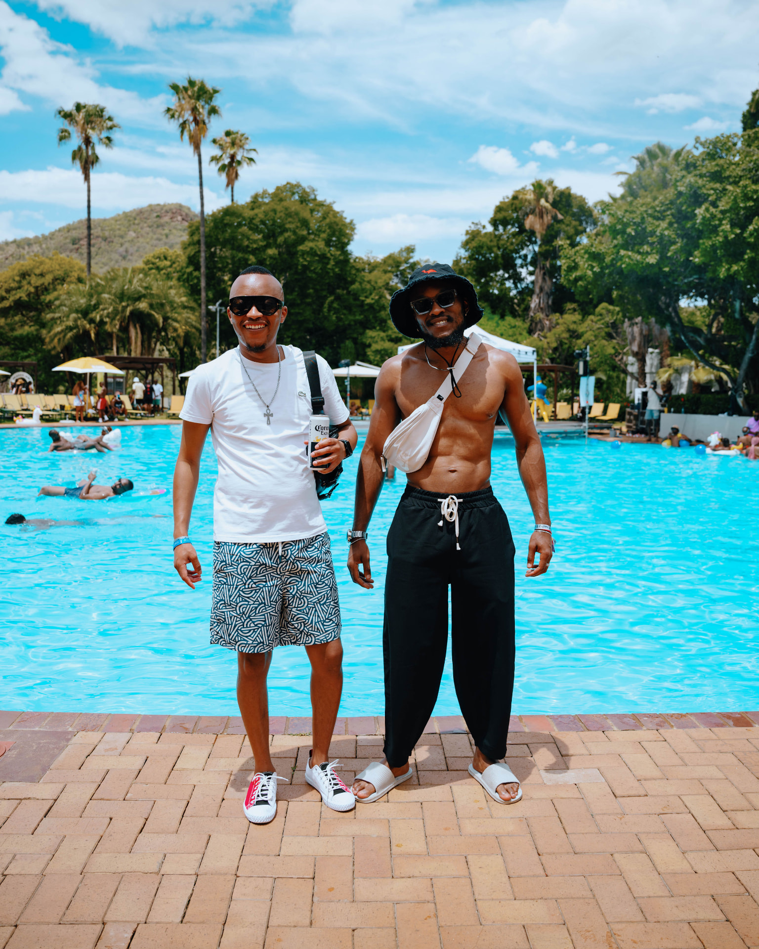 Two guests standing by the pool with palm trees behind