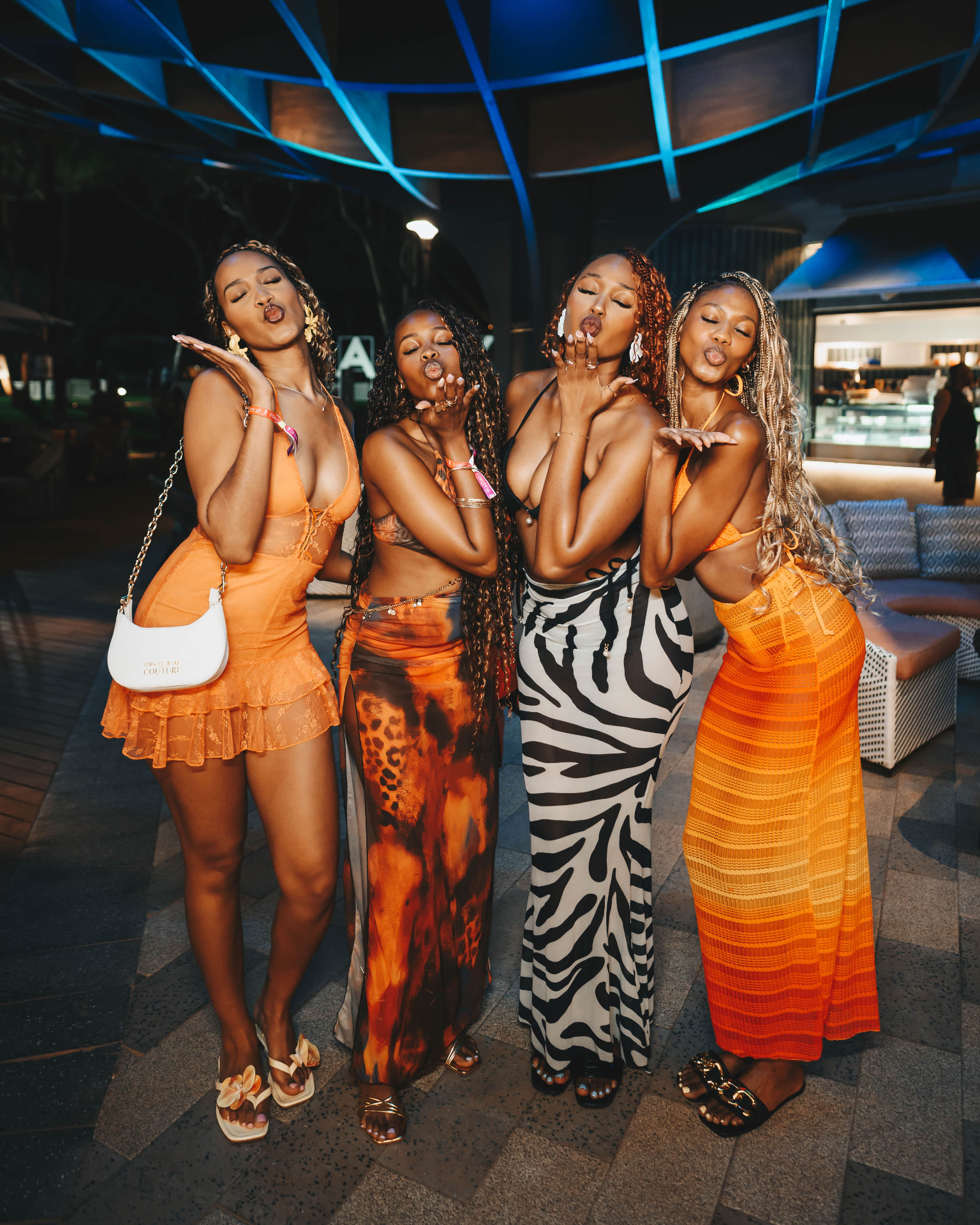 Four guests in vibrant outfits posing together at the club